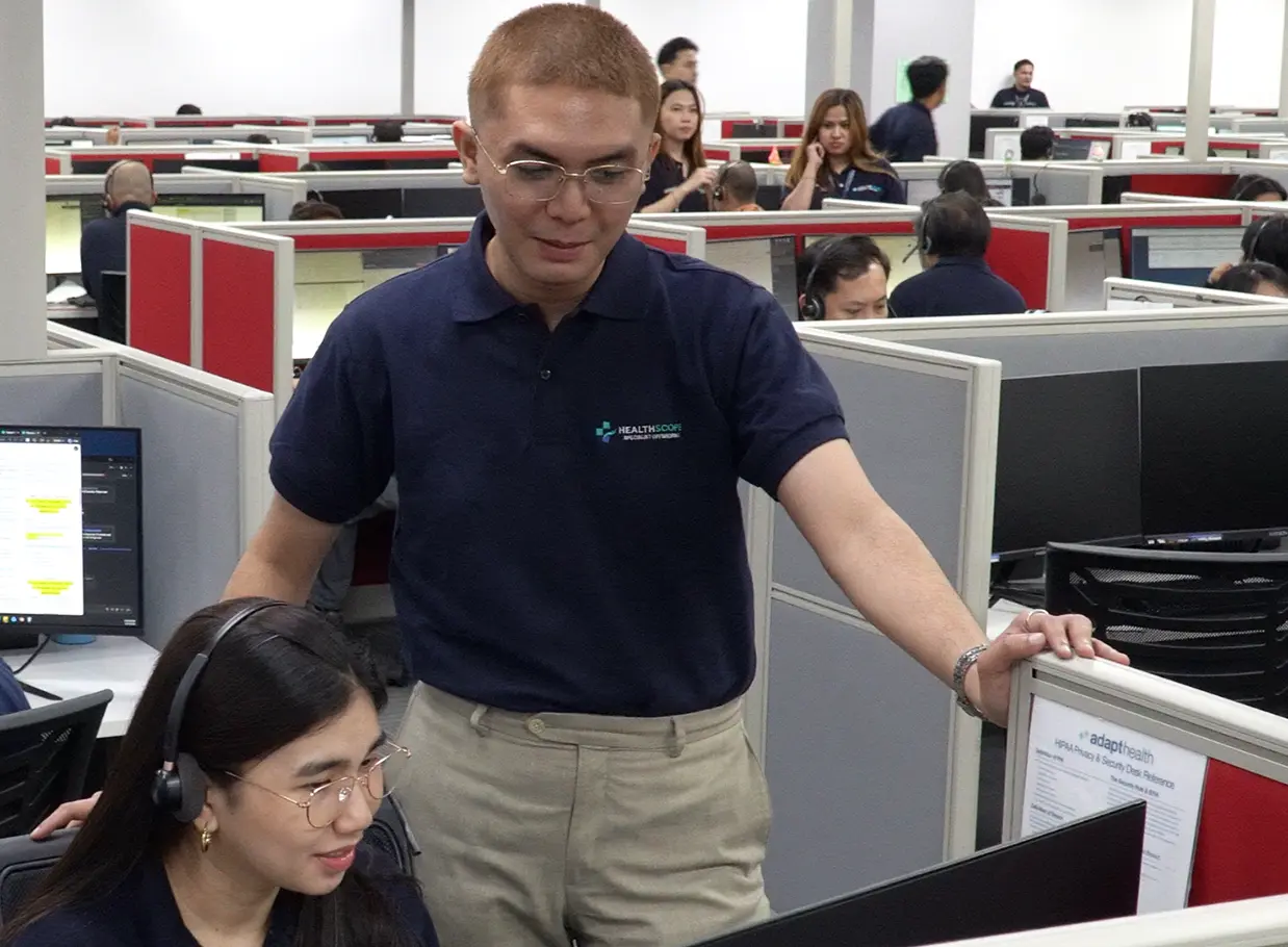 A Healthscope colleague assisting a headset-wearing teammate in the operations center